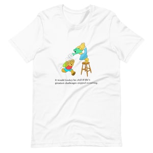 Könnte beinhalten: Ein weißes T-Shirt mit einer Cartoon-Illustration von zwei Bären. Ein Bär gießt Wasser aus einer Gießkanne auf den anderen Bären. Der Text auf dem T-Shirt lautet: "it would lowkey be chill if life's greatest challenges stopped occurring."