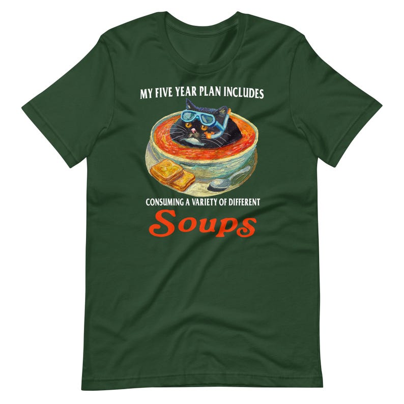 May include: Dark green t-shirt featuring a whimsical illustration of a black cat wearing goggles, submerged in a bowl of soup. The text reads "My Five Year Plan Includes Consuming a Variety of Different Soups."