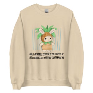May include: A beige sweatshirt with a cartoon bunny wearing a coconut costume and the text "BRO, I AM MERELY EXISTING IN THE CONTEXT OF ALL IN WHICH I LIVE AND WHAT CAME BEFORE ME".