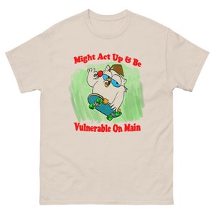 May include: A beige t-shirt with a cartoon owl on a skateboard. The owl is wearing a hat and holding a red cherry. The text "Might Act Up & Be Vulnerable On Main" is printed in red on the shirt.