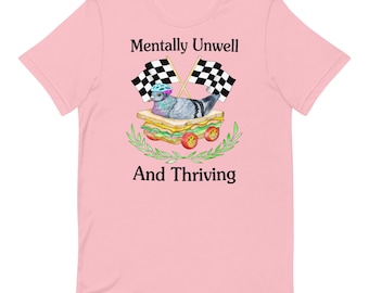Puede incluir: Camiseta rosa claro con el texto "Mentally Unwell And Thriving". El gráfico muestra una paloma con casco sobre un sándwich, con banderas a cuadros. El diseño incluye ramas de olivo y pequeñas ruedas.