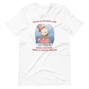 May include: White t-shirt featuring a cartoon illustration of a cat wearing a top hat and holding a red and white scarf. The text "WISHING ALL MY HATERS A VERY BEING VISITED BY THREE (3) GHOSTS TONIGHT" is printed in red on the shirt.