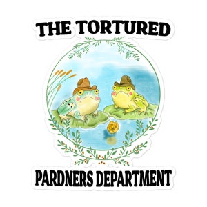 May include: A sticker featuring a cartoon illustration of two frogs wearing cowboy hats, perched on lily pads in a pond. The text "THE TORTURED" is above the image and "PARDNERS DEPARTMENT" is below.