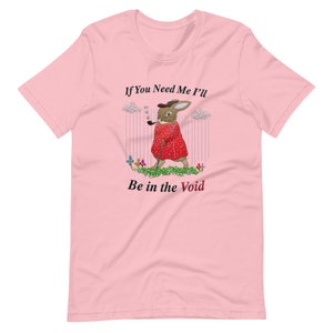 May include: Pink t-shirt featuring a whimsical illustration of a rabbit in a red coat, smoking a pipe, and holding a cane. The text on the shirt reads "If You Need Me I'll Be in the Void."