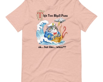 Puede incluir: Una camiseta rosa claro con un gato de dibujos animados que lleva un sombrero de capitán y dirige un barco a través de un mar tormentoso. El texto "This Too Shall Pass" está por encima del gato y "ok... but like... when???" está por debajo del gato.