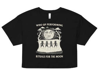 Puede incluir: Camiseta negra de corte corto con un gráfico blanco de una luna con cara y tres figuras bailando a su alrededor. El texto "WHO UP PERFORMING" y "RITUALS FOR THE MOON" está impreso en blanco.