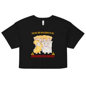 Op de afbeelding: Zwart gecropped T-shirt met een afbeelding van twee cartoon konijnen die verkleed zijn als macaroni en kaas. De tekst "You're the macaroni to my bioengineered food ingredient" staat op het shirt gedrukt.