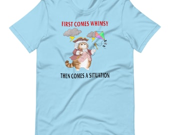 Könnte beinhalten: Ein hellblaues T-Shirt mit einer Comic-Katze, die einen rot-weißen Mantel trägt und einen Drachen hält. Der Text "FIRST COMES WHIMSY" und "THEN COMES A SITUATION" ist auf dem T-Shirt aufgedruckt.