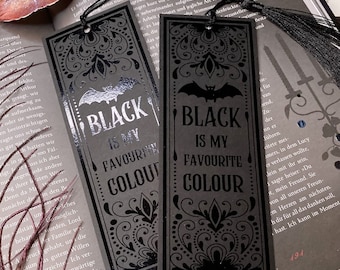 May include: Two rectangular black bookmarks with black tassels. Each features a bat illustration at the top and the text "BLACK IS MY FAVOURITE COLOUR" in a decorative font, surrounded by intricate filigree patterns in a matte and glossy finish.