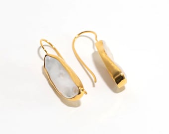 May include: A pair of gold earrings with white pearl-like stones. The earrings have a simple, elegant design.