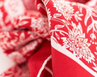 May include: Red and white patterned fabric with a floral design. The fabric is folded and the edges are trimmed with white.