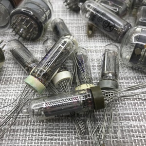 Könnte beinhalten: Eine Sammlung von Vintage-Vakuumröhren mit Glaskolben, Metallstiften und internen Komponenten. Die Röhren variieren in Größe und Form, mit sichtbaren Innenstrukturen und Drahtanschlüssen. Einige Röhren haben Markierungen.