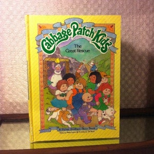 May include: A yellow book with a colorful illustration of the Cabbage Patch Kids characters on the cover. The title of the book is "The Great Rescue".