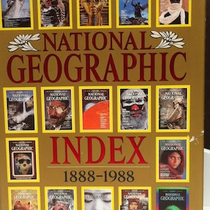May include: A gold-colored book titled "One Hundred Years National Geographic Index 1888-1988". The cover features a collage of National Geographic magazine covers from different years.