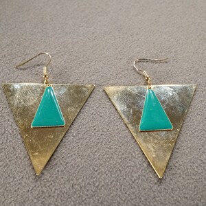 May include: A pair of gold triangle earrings with teal green triangle accents.