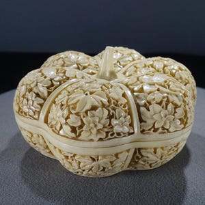 May include: A white, intricately carved, floral design, pumpkin-shaped trinket box.