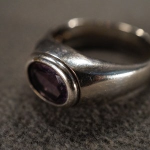 May include: A silver ring with a bezel setting featuring a purple gemstone.
