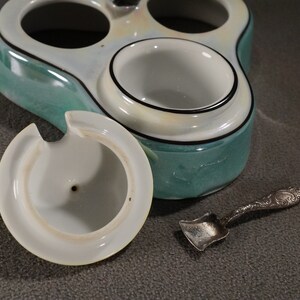 May include: A vintage ceramic condiment set with three individual containers, one with a lid. The set is decorated with a green and white glaze and black trim. A small silver spoon is included.