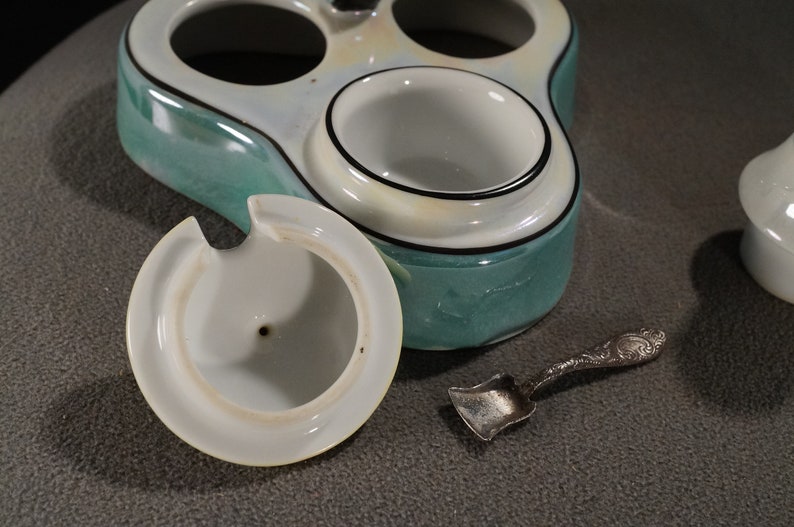 May include: A vintage ceramic condiment set with three individual containers, one with a lid. The set is decorated with a green and white glaze and black trim. A small silver spoon is included.