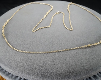 May include: A gold chain necklace with a delicate, twisted design. The chain is approximately 20 inches long.