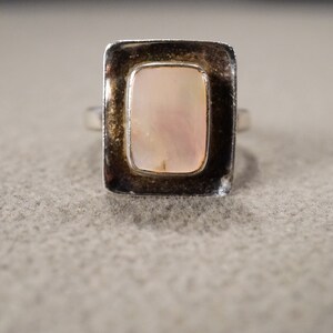 May include: A silver ring with a rectangular, iridescent pink mother of pearl stone.