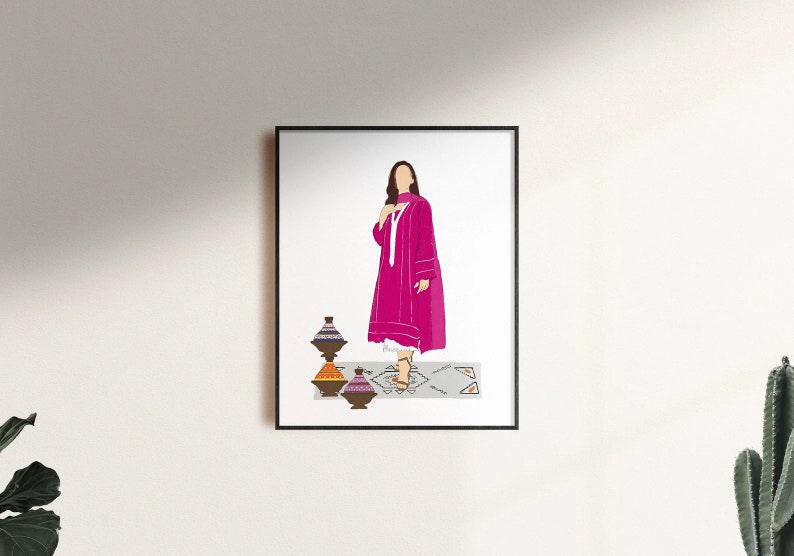 May include: A framed art print featuring a woman in a magenta dress and scarf, standing on a patterned rug. Decorative pottery in shades of brown, orange, and purple are in the foreground. The artwork is set against a white background.