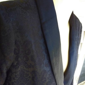 May include: A black blazer with a satin collar. The blazer has a floral pattern.