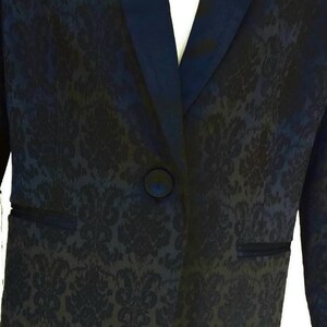 May include: A black blazer with a satin lapel and a floral pattern. The blazer has a single button closure.