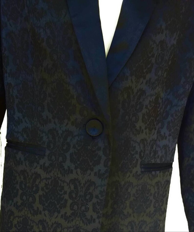 May include: A black blazer with a satin lapel and a floral pattern. The blazer has a single button closure.