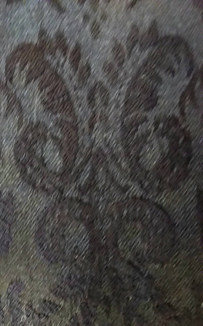 May include: A close-up of a grey and brown patterned fabric with a subtle sheen. The fabric has a textured, woven appearance.