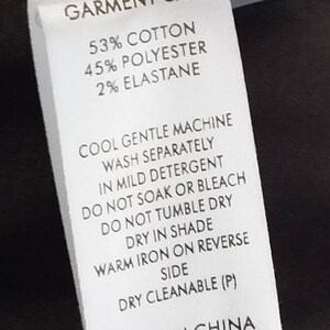 May include: A white garment care label with black text. The label states "GARMENT CARE" and lists the fabric composition as 53% cotton, 45% polyester, and 2% elastane. The label also includes instructions for washing, drying, and ironing the garment. The label states "MADE IN CHINA" and includes a product code: "S14EJW3069".