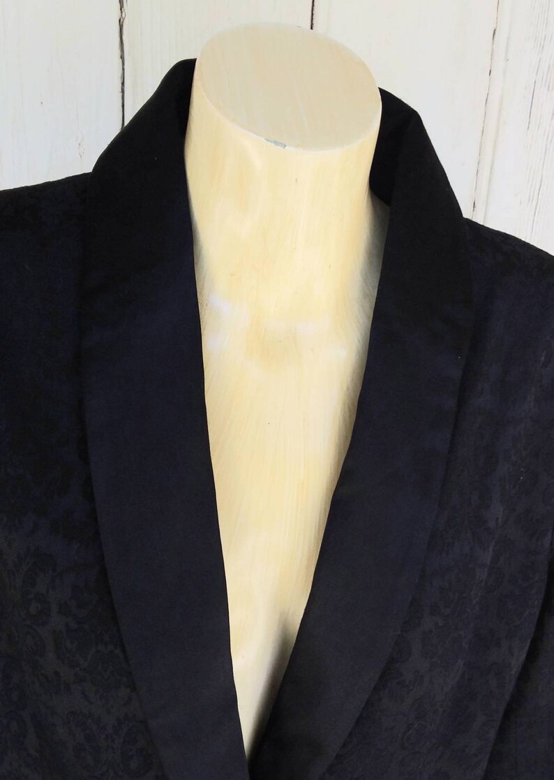 May include: A black blazer with a satin collar. The blazer has a subtle damask pattern.