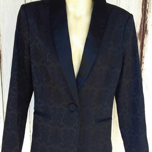May include: A black blazer with a satin collar and a floral pattern. The blazer has a single button closure.