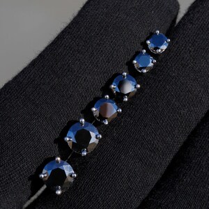 May include: A set of six black diamond earrings in various sizes, displayed on a black fabric background.