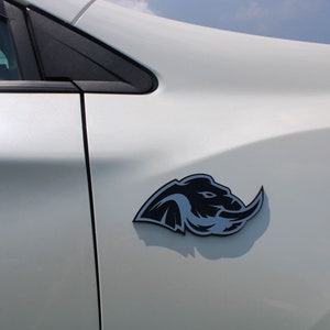 Puede incluir: Un coche blanco con un logotipo de elefante negro en el lateral.