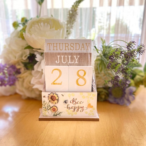 Ewiger Kalender aus Holzblock mit Bienenmotiven und den Worten ""Be Happy"" und Sonnenblumendesign in Geschenkbox."