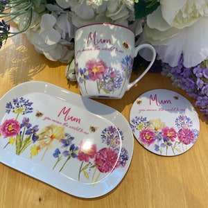 Peut inclure: Un ensemble tasse, plateau et sous-verre en céramique blanche avec un motif floral et le texte "Mum you mean the world to me".