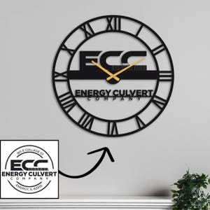 May include: Black metal wall clock with Roman numeral markings and a gold-coloured hour and minute hand. The clock face features the text "ECC Energy Culvert Company".