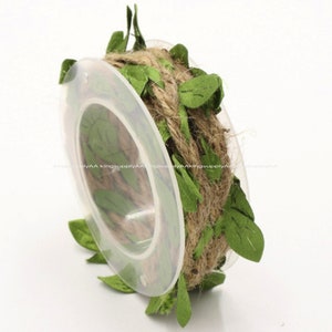 May include: A roll of twine with green fabric leaves wrapped around it. The twine is brown and the leaves are a light green.