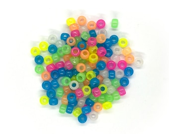 May include: A pile of colorful glow-in-the-dark round beads. The beads are in various colors, including pink, blue, green, yellow, and orange.
