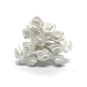 May include: A bunch of small, white satin roses. The roses are arranged in a cluster and have a delicate, romantic look.