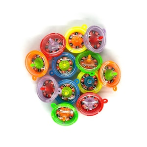 May include: A group of 11 colorful plastic spinning tops with numbers on them. The tops are in various colors, including red, orange, yellow, green, blue, and purple.