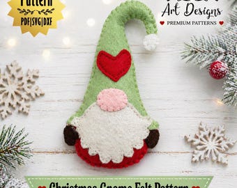 Op de afbeelding: Een vilten kerstkabouterpatroon met een groene hoed, een rood hart en een witte baard. De kabouter heeft een roze neus en een rode geschulpte onderkant. De afbeelding bevat de tekst "Christmas Gnome Felt Pattern" en "PDF | SVG | DXXF".