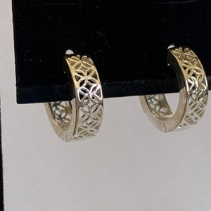 May include: A pair of silver hoop earrings with a delicate floral cutout design.