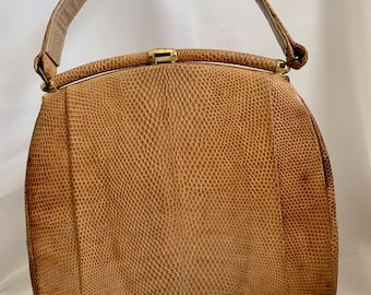 Puede incluir: Un bolso de mano de cuero marrón con cierre de broche en la parte superior y un solo asa. El bolso tiene un patrón texturizado, similar a la piel de serpiente.