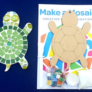 Può includere: Un kit di artigianato di tartaruga a mosaico verde e bianco. Il kit include una forma di tartaruga in legno, tessere di mosaico e adesivo. La confezione presenta il testo "Make a Mosaic" e "Creation & Imagination".
