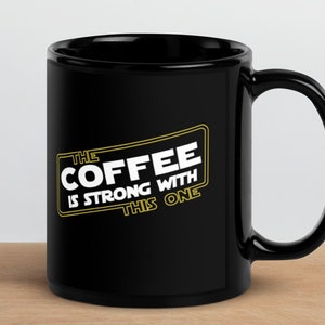 May include: Black coffee mug with a white graphic that says "The Coffee Is Strong With This One" in a yellow box.