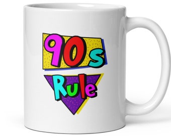 May include: White ceramic mug with a colorful graphic design that says "90's Rule" in a retro style.