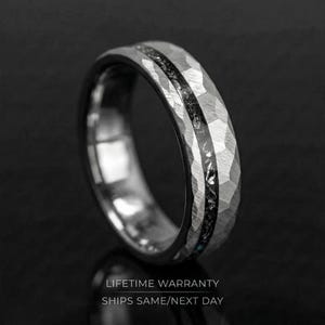 May include: A silver ring with a hammered texture and a black inlay. The ring has a dark background. The text "LIFETIME WARRANTY" and "SHIPS SAME/NEXT DAY" are at the bottom of the image.