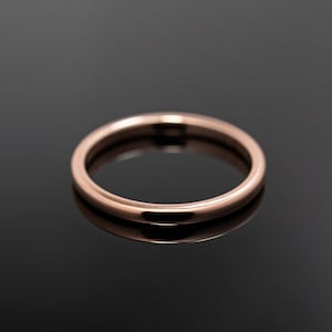 May include: A simple, thin, circular ring with a smooth, polished surface and a warm rose gold metallic finish. The band features a rounded profile and a consistent width throughout, reflecting light evenly across its curved, metallic exterior.